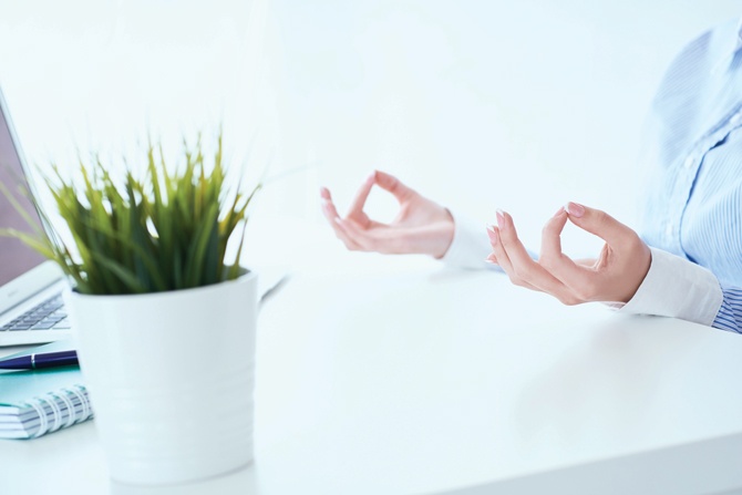 Calm businesswoman meditating at work, focus on female hands in mudra, close up view. Peaceful mindful employee practicing exercises at workplace.